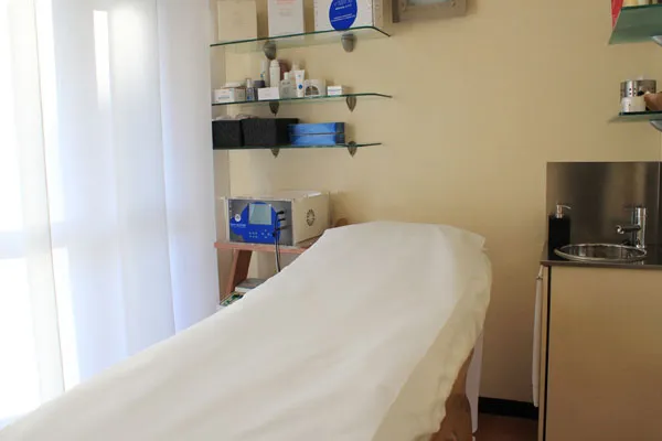 Cabina per trattamenti viso con lettino e mensole ordinate